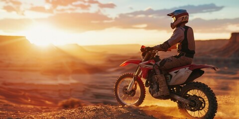 A person rides a dirt bike through the desert terrain, with sand and rocks in the background