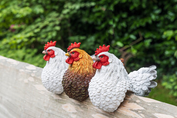 Colorful sculptured roosters sitting on a wooden bench