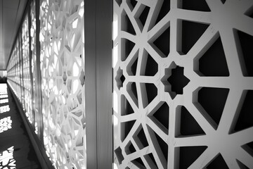 Obraz premium Image of walls with intricate geometric patterns casting shadows, showcasing a detailed design inspired by traditional ornamentation, emphasizing light and structure.