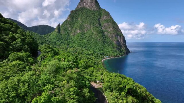 The Pitons in Saint Lucia with lush greenery and coastal waters. Iconic mountain peak and Caribbean shoreline. Scenic natural landscape. Aerial.