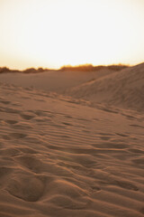 sunset in the desert, sandy dunes closeup, orange sky, backlit vertical landscape, traces on sand. Gran Canaria, Canary Islands, Spain.