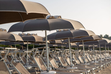 A row of chairs and umbrellas on a sandy beach under the sky