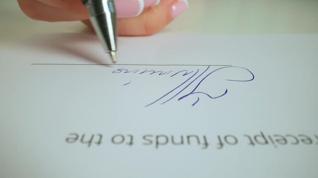 Close up shot of woman hand working with document, pen in female hand writing a personal signature in financial or business document.