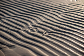 A close up image of a sandy surface with gentle waves