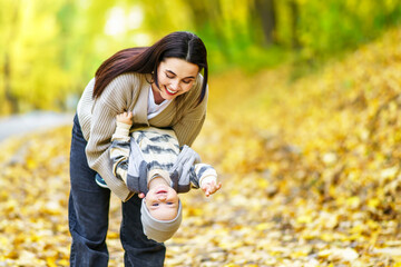 Mother holding child upside down in autumn park