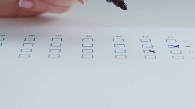Close up shot of woman at the desk working with important exam document, student reading and crossing check boxes in test, crossing out with marker.
