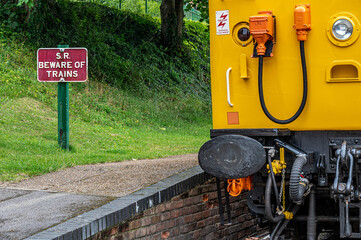 Front of a stationary diesel train alongside a beware of trains sign at the Watercress Line, Alresford, Hampshire, UK