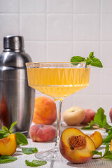 Peach martini or margarita or lemonade cold fruit drink, summer iced fruit juice cocktail with mint and lemon, on white wooden table