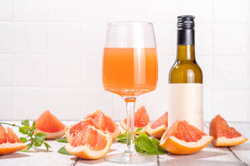 Grapefruit Wine glass and bottle with sliced pink grapefruit and mint, citrus rosé wine with grapefruits