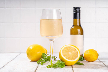 Lemon Wine glass and bottle with sliced and whole lemons and mint, tasty delicious citrus white wine 