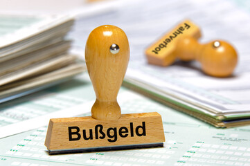 Ein Holzstempel ist beschriftet mit dem Aufdruck: Bußgeld