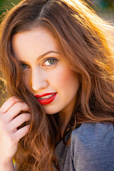 Close up portrait of a beautiful smiling young woman, with her long brown hair back lit by the late afternoon sunlight. 