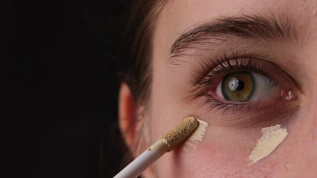 Close-Up Shot Of A Girl Applying Concealer Under Her Eyes And Makeup Foundation On Her Eyelids