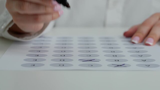 Close up shot of woman at the desk working with important exam document, student reading and picking answers in test, crossing out with marker letters questions.