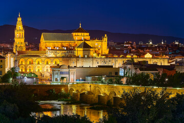 Fototapeta premium Night panoramic view of the Mosque-Cathedral across the Calahorra Tower and the Roman Bridge over the Guadalquivir River, Cordoba, Andalusia, Spain.