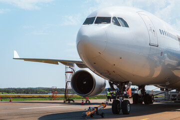 A wide-body passenger jet airliner undergoes pre-takeoff servicing and fueling on the apron on a...