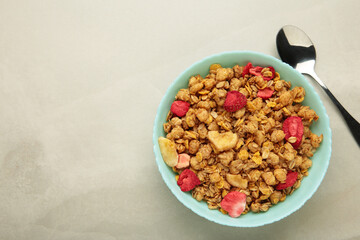 Granola with strawberries in a bowl on light background.