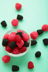 Raspberry and blackberry candy on bowl on mint background. Top view