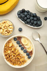 Oat raisin granola with fresh summer berries in a bowl on light background. Vertical photo