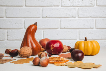 Yellow and red pumpkins on a light background with red apples, dry leaves, chestnuts. Autumn composition, fall. Halloween background. Front view