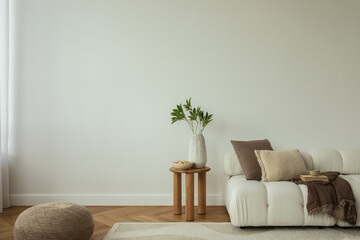 A modern living room with a white sofa, wooden side table, and neutral decor. Home decor.  Books, slippers, and a coffee cup add a cozy touch. Template. Copy space.