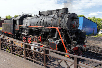 Black retro steam locomotive from USSR times is near the station