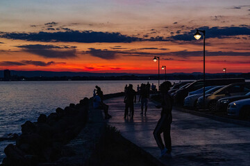 people walk along the promenade after sunset