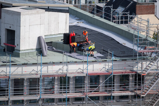 Birdseye view of roofer waterproofing the flat roof of a commercial building.