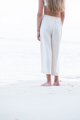 a girl stands on the ocean shore and looks into the distance, white sand