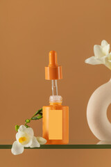 Enjoy the simplicity of a minimalist orange serum and floral vase displayed on a glass shelf. Skin care