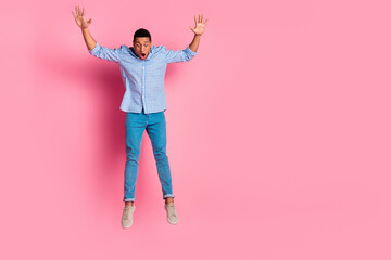 Full length photo of handsome carefree guy wear plaid shirt jumping falling emtpy space isolated pink color background