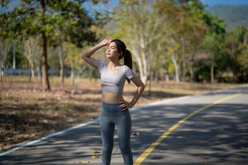 A woman is standing on a road, wearing a grey shirt and grey pants