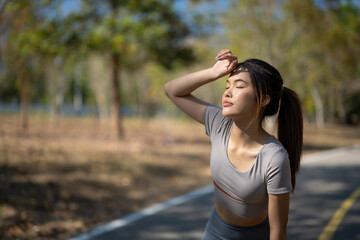 A woman is standing on a road, wearing a grey shirt and ponytail