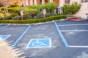 Outdoor parking spaces with symbols painted on ground indicating they are reserved for people with disabilities. Concept of accessibility.