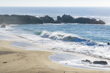 Big waves crashing on a sandy beach on the coast of California on a sunny fall day