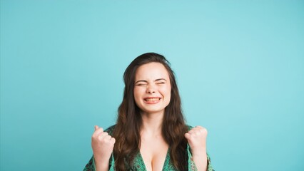 Fototapeta premium Successful young woman clenching fists in blue studio