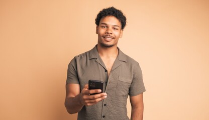 Smiling young man using smartphone in beige studio