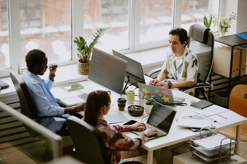 Biracial highly skilled programmer team writing codes surrounded by digital devices, coffee and...