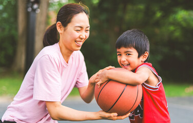 Basketball, family and teaching sport with a mom and son training on a court outside for leisure fitness and fun