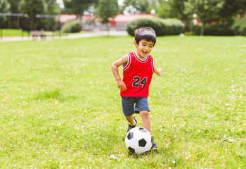 nice and handsome child boy play football outside