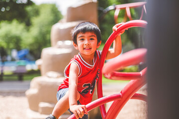 Cute little kid boy having fun while playing on the playground in the daytime in summer. © Louis-Paul Photo