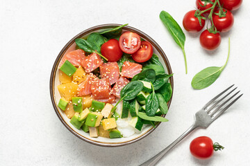 Salmon bowl with spinach, rice, avocado, tomato, cucumbers on a white background, top view. Poke bowl, healthy eating