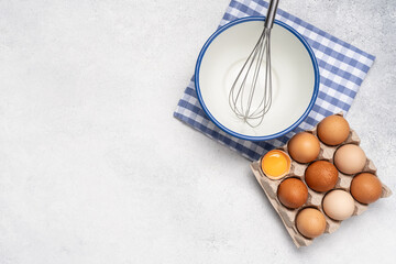 Eggs, bowl and whisk on white background with copy space. Baking background top view