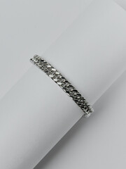 A silver bracelet with an intricate weave on a white background. An elegant decoration with a unique design, suitable for any occasion.