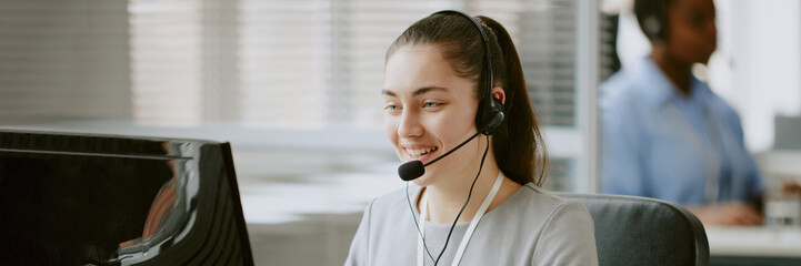 Website header of Caucasian female operator sitting at work desk while having clients call via...