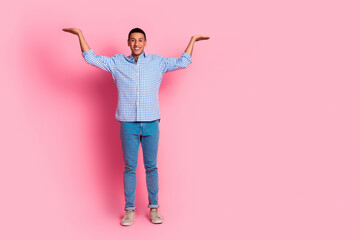Full length photo of handsome confident guy wear plaid shirt comparing arms emtpy space isolated pink color background