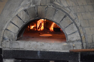 A traditional chef and pizza maker baking in a stone oven with fire