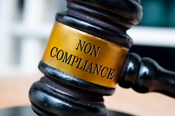 Non Compliance text engraved on lawyer gavel. Law and compliance concept.
