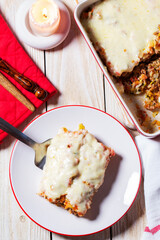 Cannellone with meat filling, tomato sauce and cheese on a light wooden table.