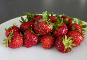 Strawberries on a white plate on a dark kitchen countertop